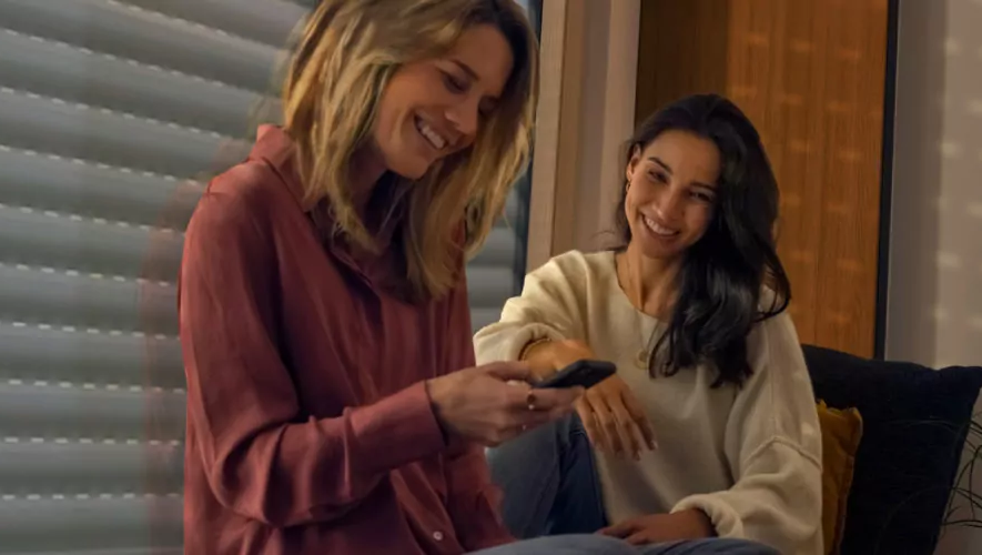 Zwei Frauen steuern ihr Smart Home komfortabel über die Somfy Smartphone App an.