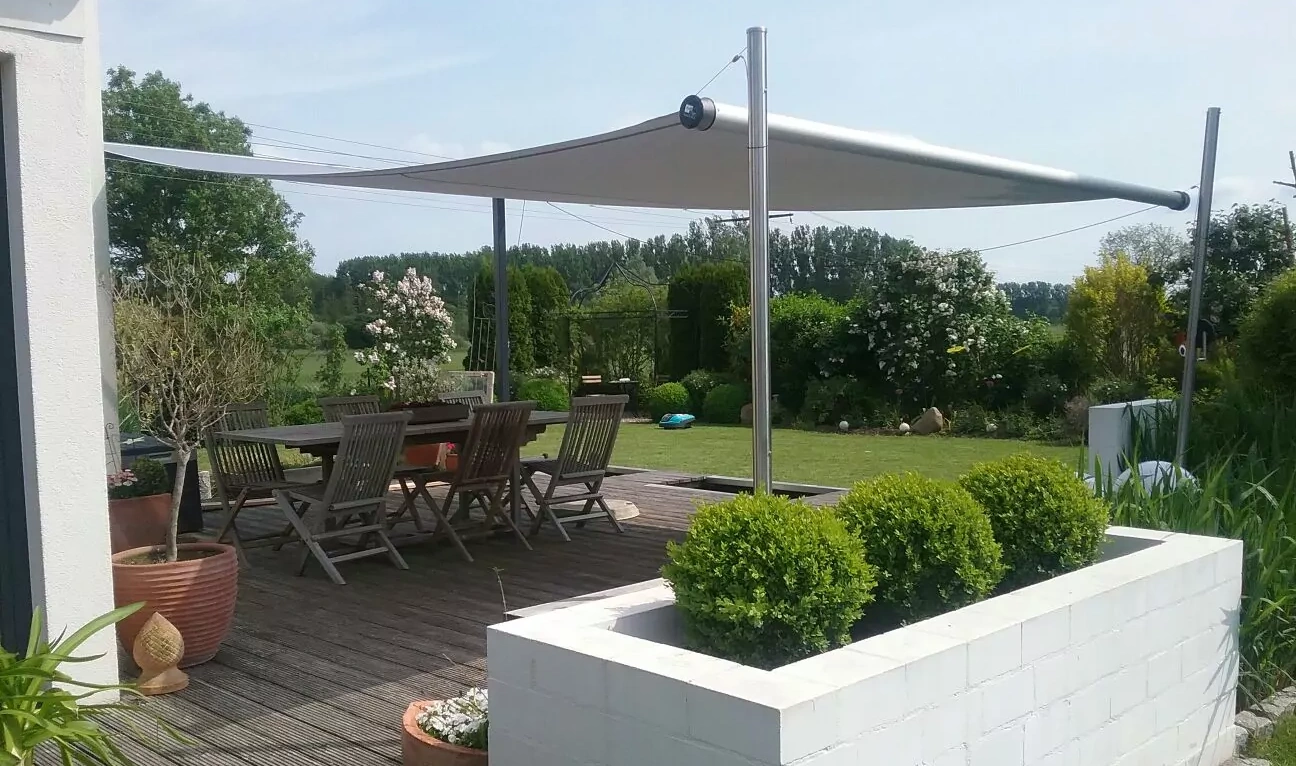 Das Sonnensegel Shadesign Shade FRAME freistehend über einem Sonnendeck mit Sitzbereich.