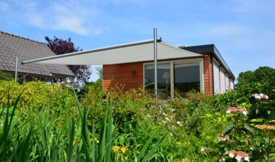Das Sonnensegel Shadesign Shade INOX als Sonnenschutz vor einem Bungalow im Grünen.