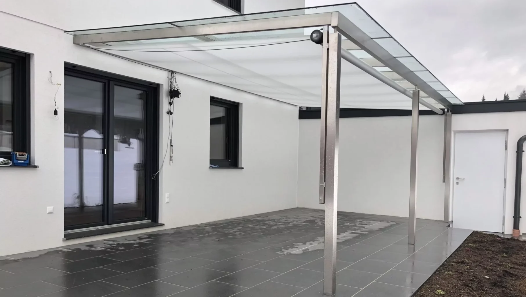 Das Sonnensegel Shadesign Shade STRUCTURE angebracht unter einem Glas-Vordach.
