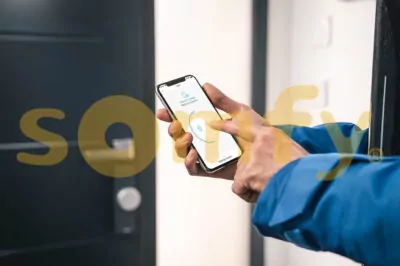 Logo der Firma Somfy vor Bedienung eines Smart-Homes an einem Smartphone.